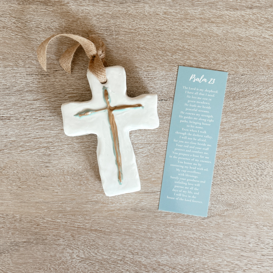 White ceramic cross with gold accents and covered in resin, accompanied by a Psalm 23 bookmark
